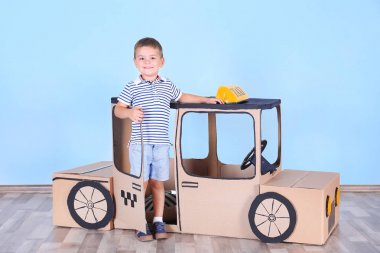 Küçük çocuk ışık odada karton taksi ile oynarken