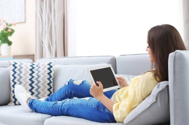 Tablet bilgisayar evde kanepede kullanan genç kadın
