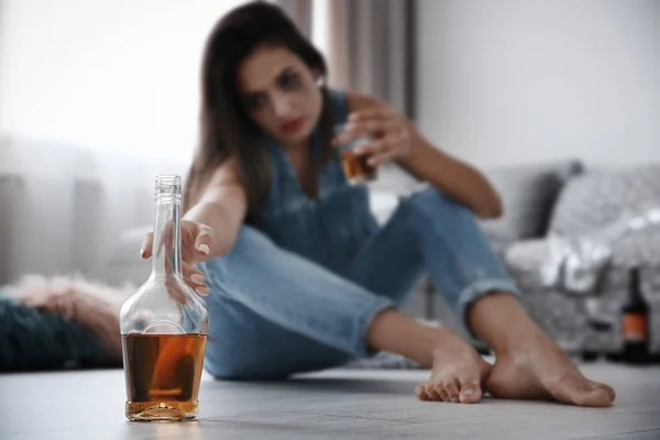 Botella con alcohol y mujer sobre fondo —  Fotos de Stock