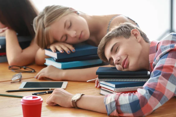 Tired students sleeping at table — Stock Photo, Image