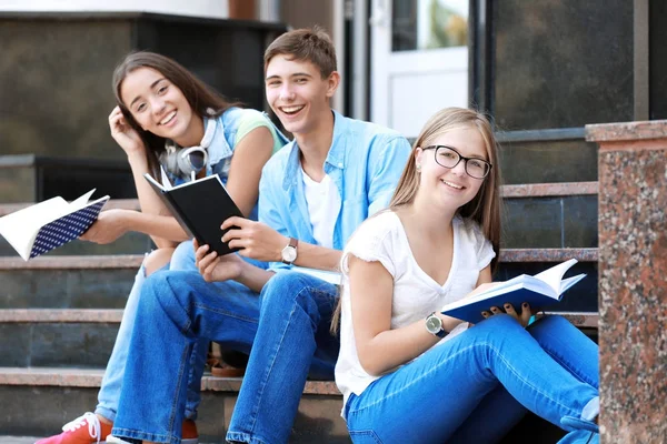 Studenti čtení zatímco sedí na schodech venku — Stock fotografie