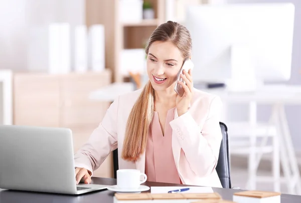 Young woman talking on phone in office — Stock Photo, Image