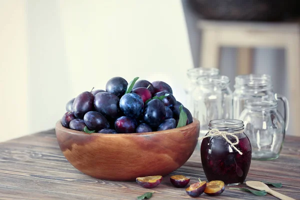 Bowl with plums and jar — Stock Photo, Image