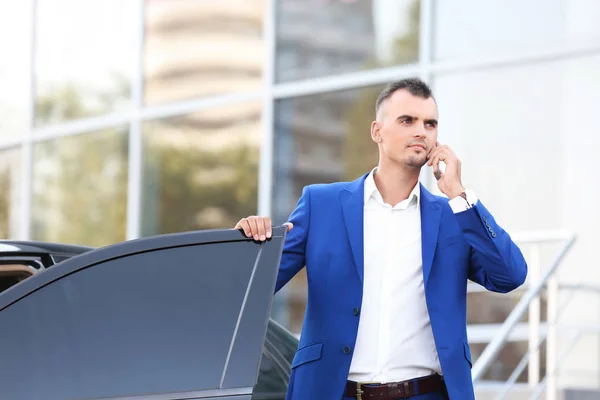 Tânăr om de afaceri vorbind la telefon lângă mașină — Fotografie, imagine de stoc