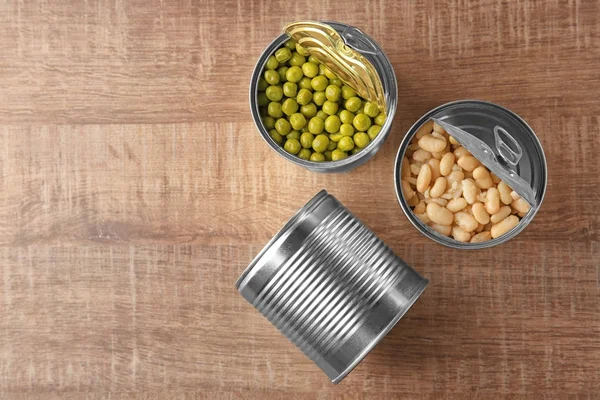Blechdosen mit verschiedenen Lebensmitteln auf Holzgrund — Stockfoto