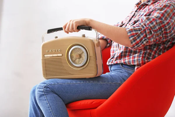 Giovane donna con radio retrò seduta su sfondo chiaro — Foto Stock