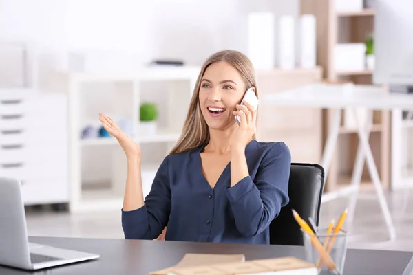 Young woman talking on phone in office — Stock Photo, Image