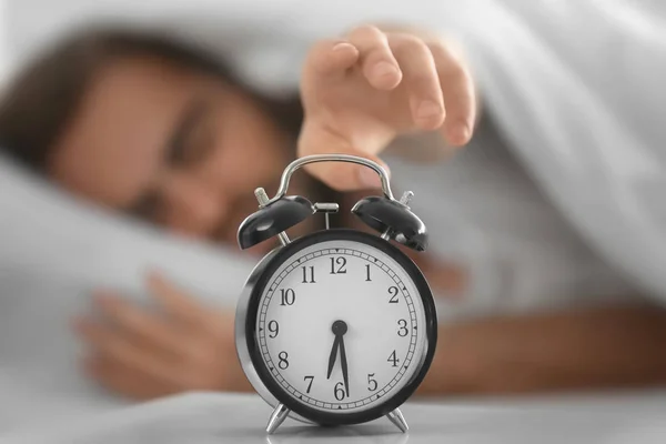 Young man switching off alarm clock signal while lying in bed at home — Stock Photo, Image