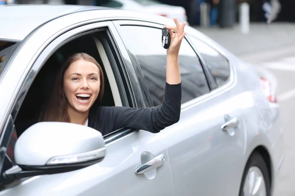 Jeune femme avec des clés sur le siège du conducteur de la voiture — Photo