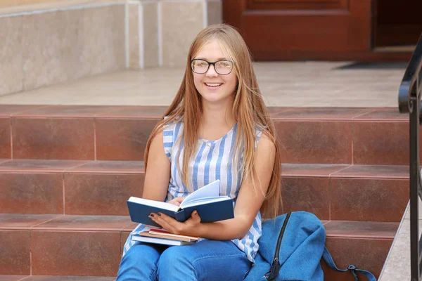 Estudiante leyendo libro mientras está sentado en escaleras al aire libre — Foto de Stock