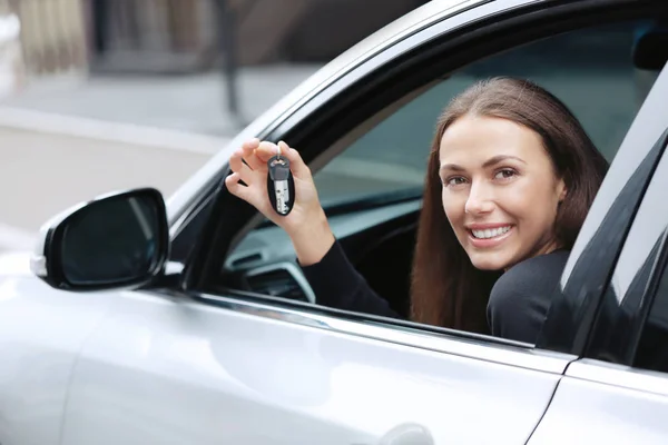 Mujer joven con llaves en el asiento del conductor del coche —  Fotos de Stock