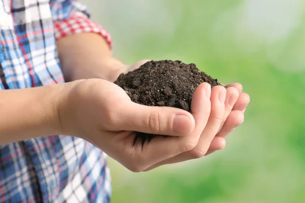 Woman holding handful of soil on blurred background — Stock Photo, Image