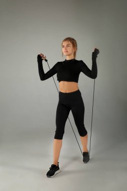 Gri arka plan üzerinde ip atlama ile sportif genç kadın