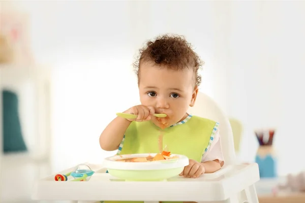 Pequeño bebé comiendo puré de frutas en el interior — Foto de Stock