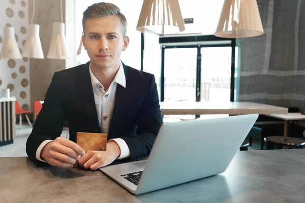 Jeune homme utilisant ordinateur portable et carte de crédit pour les achats en ligne à la table — Photo