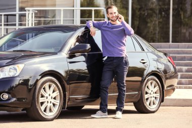 Yakışıklı genç adam araç açık havada yakınındaki cep telefonunda konuşuyor