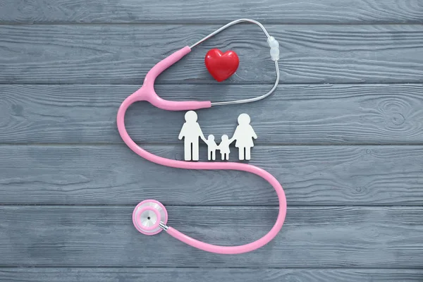 Family figure, red heart and stethoscope on wooden background — Stock Photo, Image