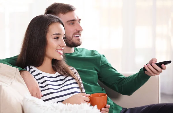 Jovem casal assistindo tv no sofá em casa — Fotografia de Stock