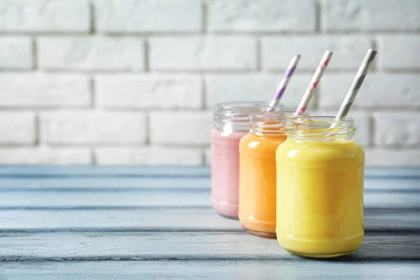 Frascos con delicioso batido en mesa de madera — Foto de Stock