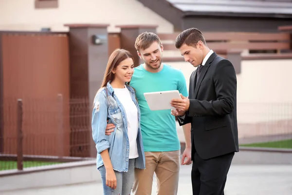 Junges Paar mit Immobilienmakler in Hausnähe — Stockfoto