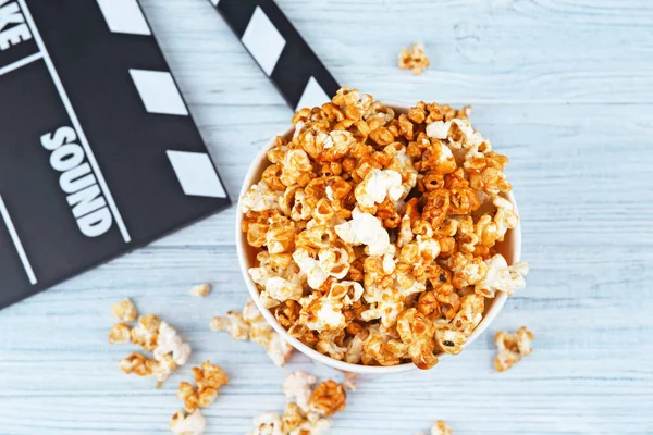 Kopp med karamell popcorn och film kläpp — Stockfoto