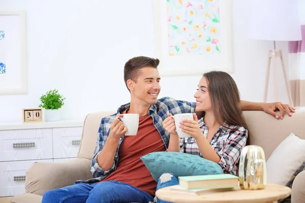 Jeune couple boire du thé sur le canapé à la maison — Photo