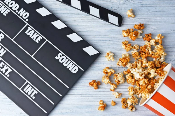 Pappbecher mit Karamell-Popcorn und Filmklöppel — Stockfoto