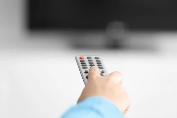Woman with TV remote control switching channels, closeup