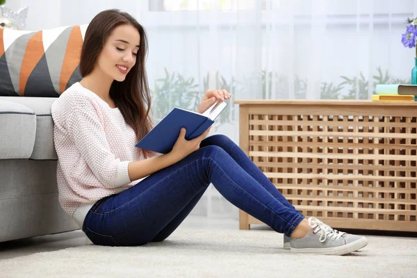 Молода жінка читає книгу на підлозі — стокове фото