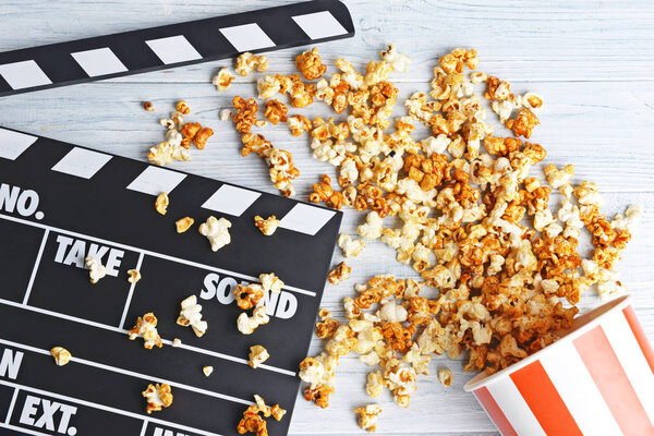 Paper cup with caramel popcorn and movie clapper 