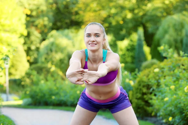 Sportliche junge Frau turnt im Park — Stockfoto