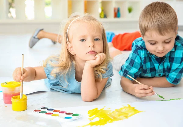 Дети лежат на полу в светлой комнате и рисуют — стоковое фото