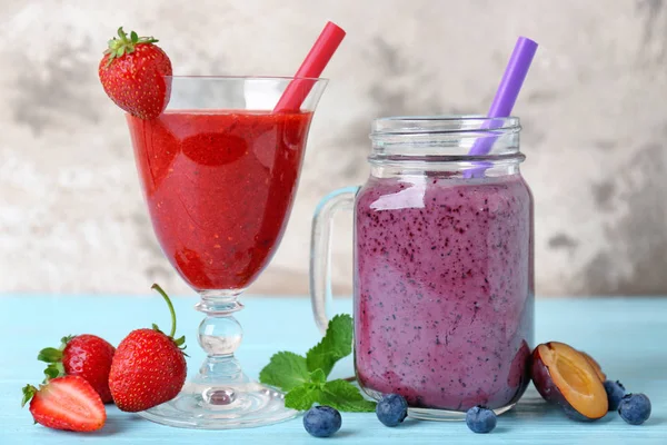 Gläser mit verschiedenen Smoothies auf dem Tisch vor grauem Hintergrund — Stockfoto