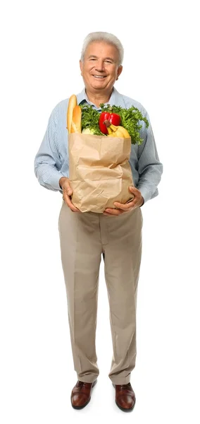 Elderly man holding paper bag with groceries on white background — Stock Photo, Image