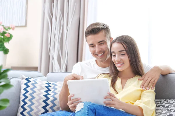 Молодая пара с помощью планшетного компьютера на диване дома — стоковое фото