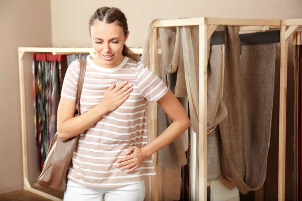 Heart attack concept. Young woman suffering from chest pain in store