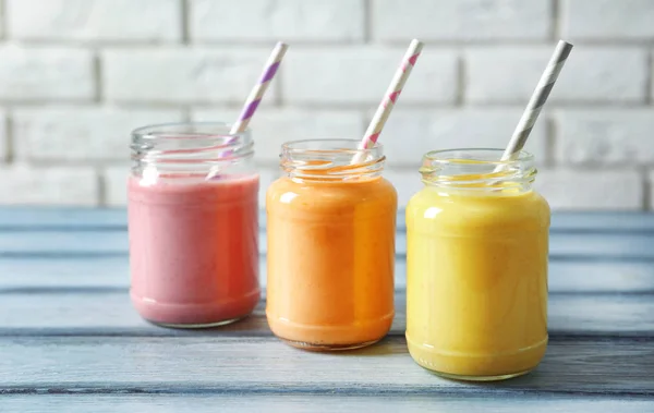 Jars with yummy smoothie on wooden table — Stock Photo, Image
