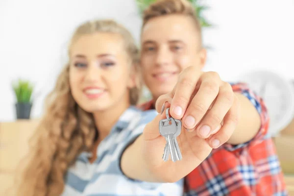 Propietarios felices sosteniendo llaves de su nueva casa, en el interior — Foto de Stock