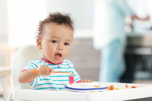 Little baby eating puree indoors — Stock Photo, Image