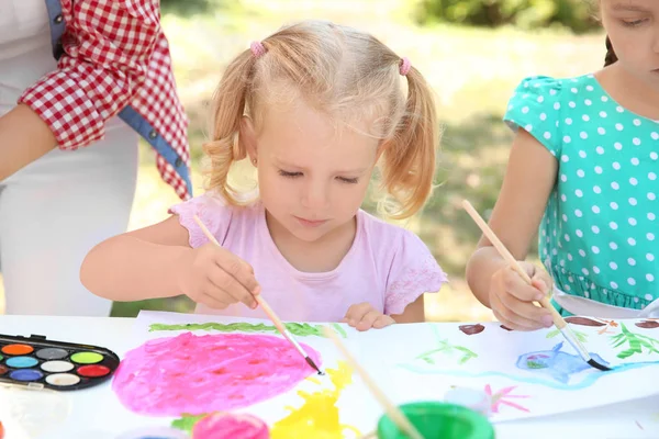 Маленькая девочка на уроке живописи на открытом воздухе — стоковое фото