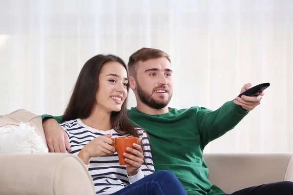 Молодая пара смотрит телевизор на диване дома — стоковое фото