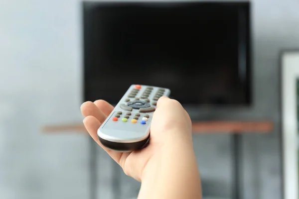 Woman with TV remote control switching channels, closeup — Stock Photo, Image