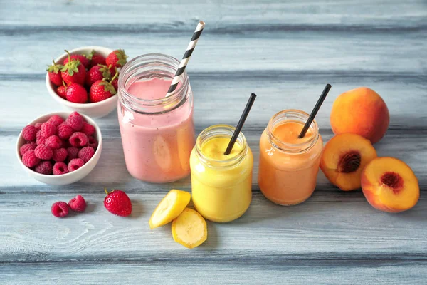 Composición con frascos de delicioso batido sobre mesa de madera — Foto de Stock