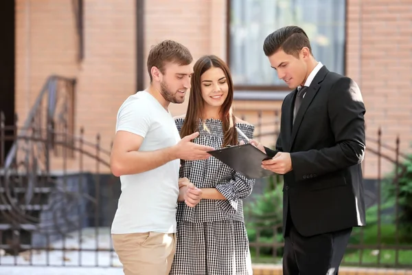 Young couple with real estate agent near house — Stock Photo, Image