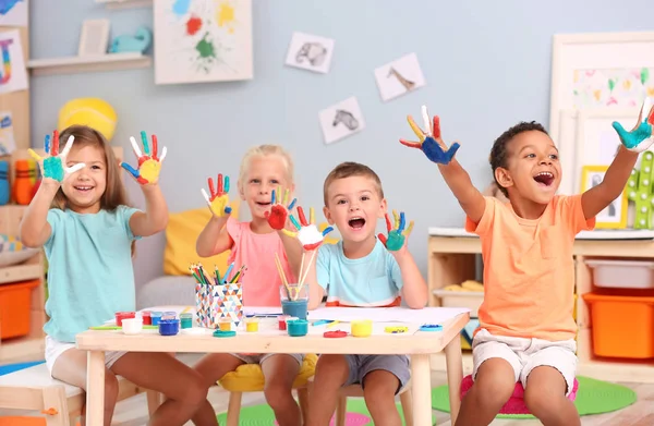 Lindos niños con palmas pintadas en la mesa interior — Foto de Stock