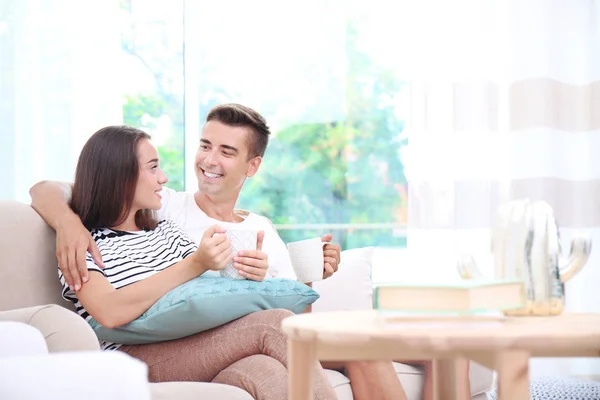 Молодая пара пьет чай на диване дома — стоковое фото