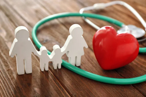 Family figure, red heart and stethoscope on wooden background — Stock Photo, Image