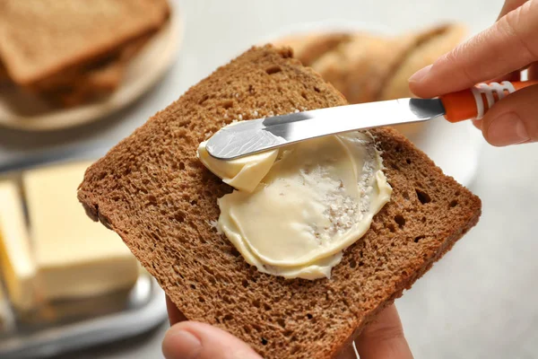 Mujer esparciendo mantequilla en rebanada de pan —  Fotos de Stock