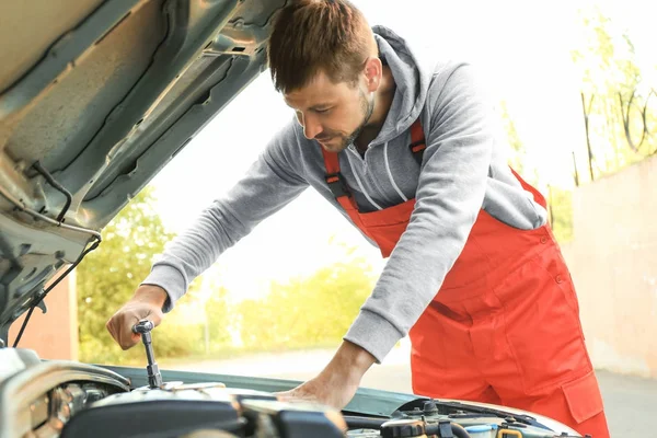 Unga manliga mekaniker reparerar bil vid service station — Stockfoto