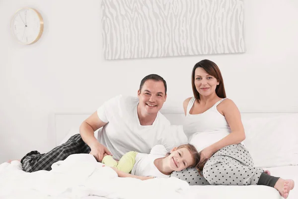 Felice giovane famiglia sul letto a casa — Foto Stock